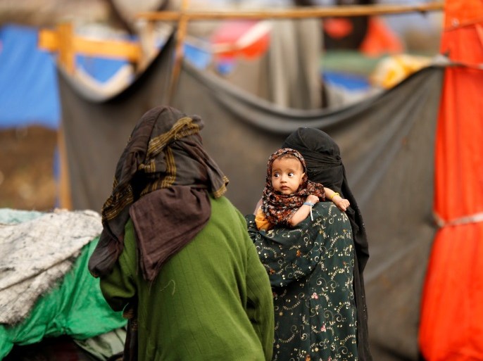 A woman carries a child near their tent at a camp for internally displaced people (IDPs) near Sanaa, Yemen March 17, 2018. Picture taken March 17, 2018. REUTERS/Khaled Abdullah