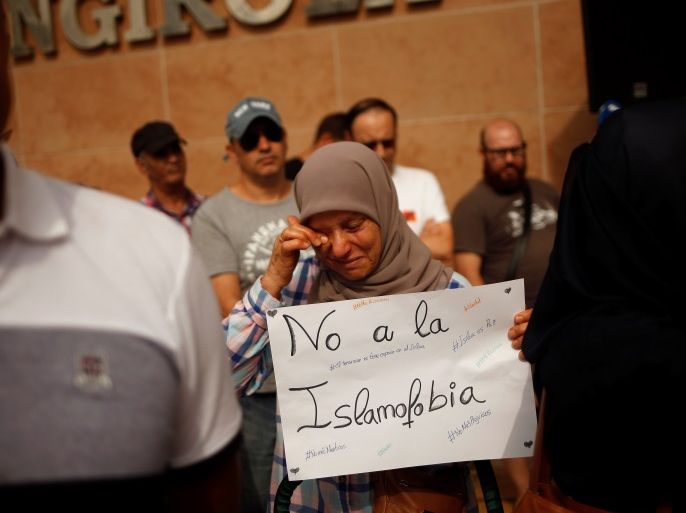 A Muslim woman, holding a sign that reads