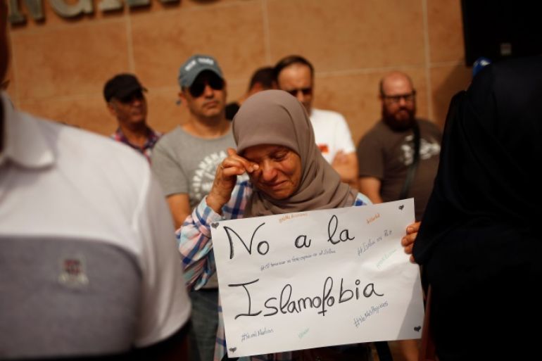 A Muslim woman, holding a sign that reads