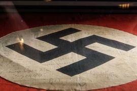 LONDON, ENGLAND - MARCH 15: A gallery assistant poses with a captured Nazi swastika flag, signed by original members of the SAS, listing their missions in Africa during World War II, at the National Army Museum on March 15, 2018 in London, England. 'Special Forces: In the Shadows' is a new exhibition, exploring the background and equipment used by the British Army Special Forces, and runs from 17 March to 18 November 2018. (Photo by Leon Neal/Getty Images)