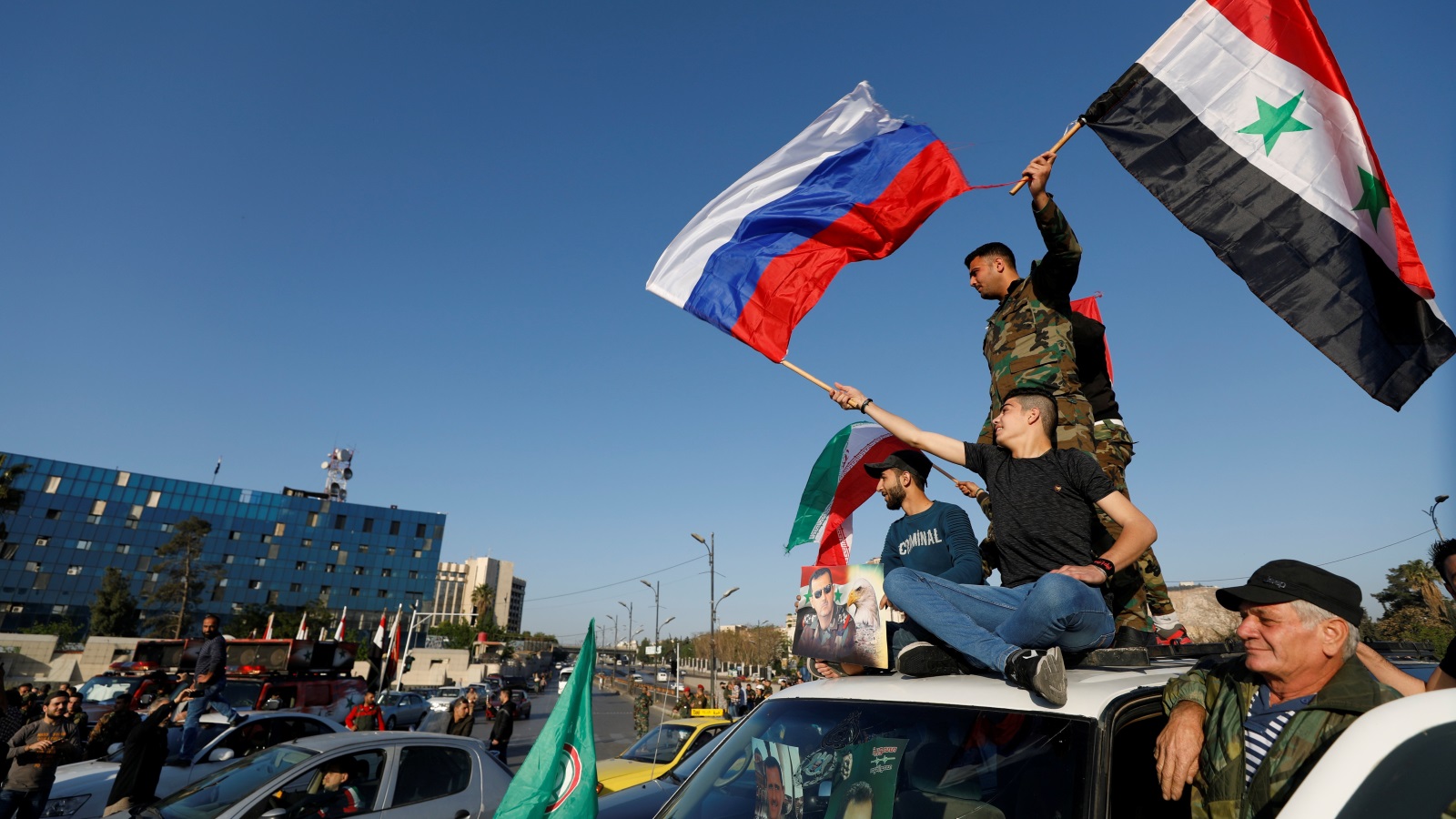 ‪سوريون في دمشق يرفعون أعلام سوريا وروسيا وإيران‬  (رويترز-أرشيف)