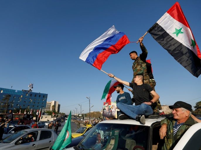 Syrians wave Russian and Syrian flags during a protest against U.S.-led air strikes in Damascus,Syria April 14,2018.REUTERS/ Omar Sanadiki