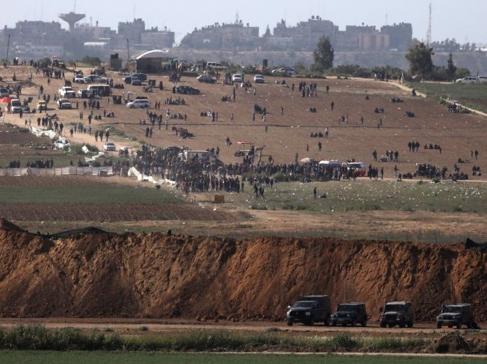 Israeli military vehicles are seen next to the border on the Israeli side of the Israel-Gaza border, as Palestinians demonstrate on the Gaza side of the border, March 31, 2018. REUTERS/Ammar Awad