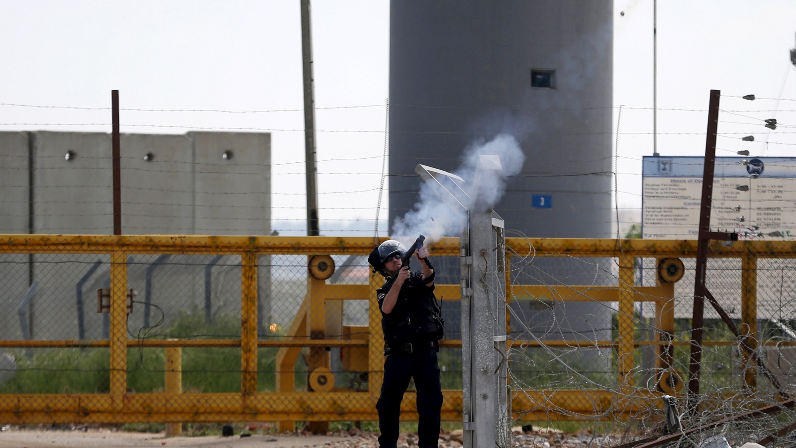 جندي إسرائيلي يطلق الغاز المدمع على متظاهرين فلسطينيين أمام سجن عوفر القريب من رام الله بالضفة الغربية (رويترز)
