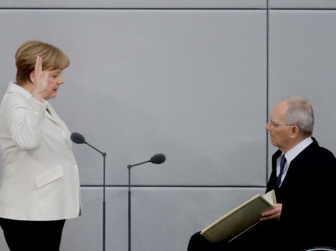 BERLIN, GERMANY - MARCH 14: German Chancellor Angela Merkel takes her oath to serve her fourth term as chancellor as Bundestag President Wolfgang Schaeuble holds up a copy of the German Constitution following her election by the Bundestag on March 14, 2018 in Berlin, Germany. Members of the new German government, a coalition between Christian Democrats (CDU/CSU) and Social Democrats (SPD), were sworn in today and will begin work immediately. The new government took the