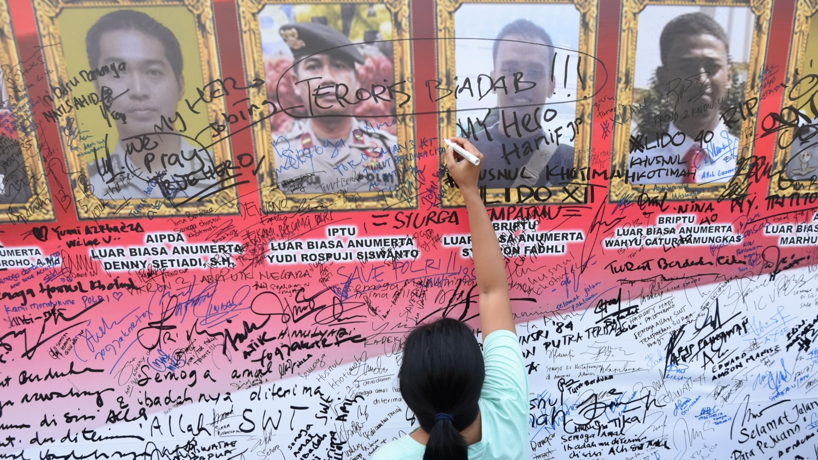 توقيعات تضامن ومواساة على ملصق لضباط الشرطة الذين قتلوا في أحداث شغب في سجن شديد الحراسة في جاوا الغربية (رويترز)