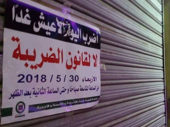 يافطة معلقة على بوابة محال تجارية تدعو للإضراب بالأردن احتجاجا على قانون ضريبة الدخل