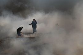 GAZA CITY, GAZA - MAY 15: Two women struggle in a cloud of tear gas at the border fence with Israel on May 15, 2018 in Gaza City, Gaza. Israeli soldiers killed over 50 Palestinians and wounded over a thousand as demonstrations on the Gaza-Israel border coincided with the controversial opening of the U.S. Embassy in Jerusalem yesterday. This marks the deadliest day of violence in Gaza since 2014. Gaza's Hamas rulers have vowed that the marches will continue until the d