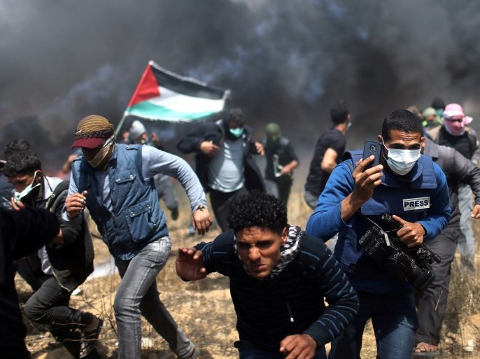 A journalist runs during clashes between Israeli troops and Palestinians in a protest at the Israel-Gaza border in the southern Gaza Strip, April 27, 2018. Picture taken April 27, 2018. REUTERS/Ibraheem Abu Mustafa
