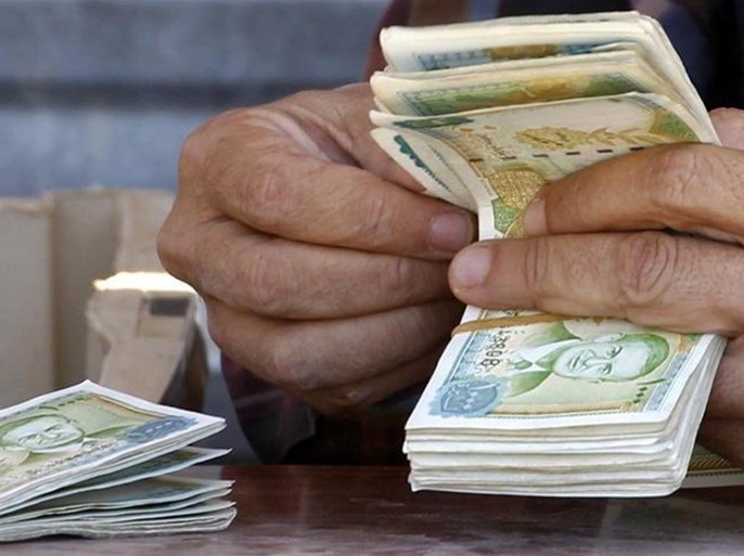 تاجر عملة يعد أوراق نقدية لليرة السورية. صورة من أرشيف رويترز