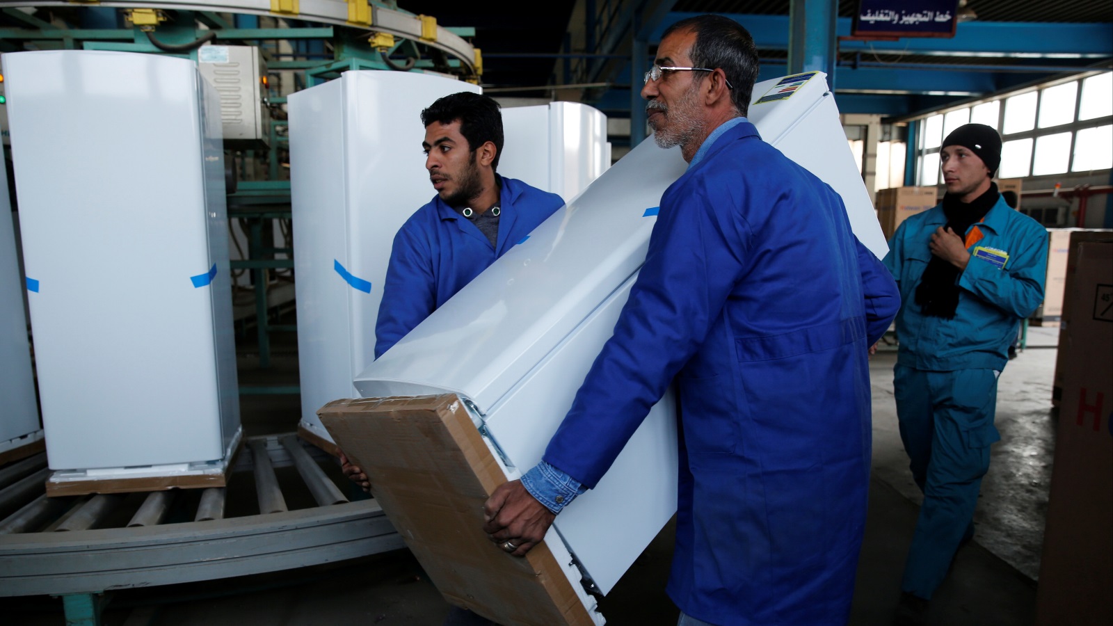 ‪عمال ينقلون ثلاجة في مصنع تابع لشركة حلوان بضواحي القاهرة‬ (رويترز)