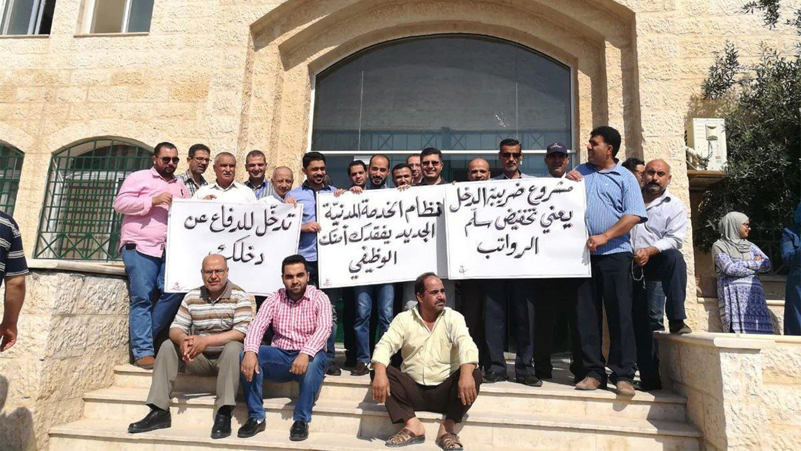 ‪موظفون مشاركون في الإضراب يرفعون لافتات رافضة لتعديلات على قانون ضريبة الدخل‬  (الصحافة الأردنية)