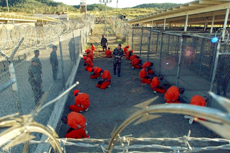 Detainees in orange jumpsuits sit in a holding area while watched by U.S. military police at the temporary Camp X-Ray, which was later closed and replaced by Camp Delta, inside Guantanamo Bay naval base in a January 11, 2002 file photo. President Barack Obama launched a final push on Tuesday to persuade Congress to close the U.S. military prison at Guantanamo Bay, Cuba, but lawmakers, opposed to rehousing detainees in the United States, declared his plan a non-starter.