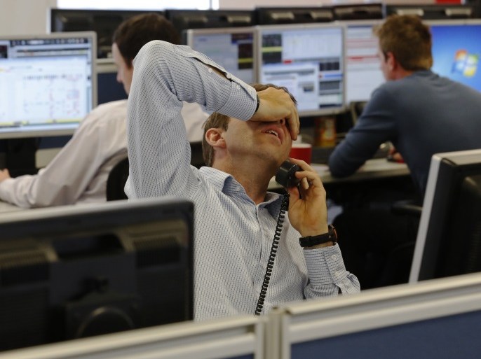 A dealer reacts while speaking with a client on the trading floor at financial spread betting company IG Index in the City of London August 7, 2013. Britain's top share index extended losses on Wednesday after the Bank of England (BoE) pledged to keep interest rates low for a longer period, but expressed caution about the fragile economic recovery. REUTERS/Luke MacGregor (BRITAIN - Tags: BUSINESS POLITICS)