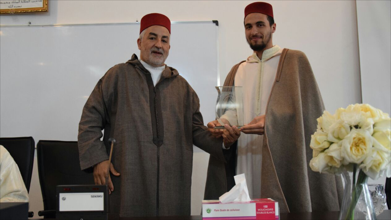 معاذ يتسلّم درع معهد محمد السادس للقراءات والدراسات القرآنية من مديره خالد الساقي(الجزيرة)