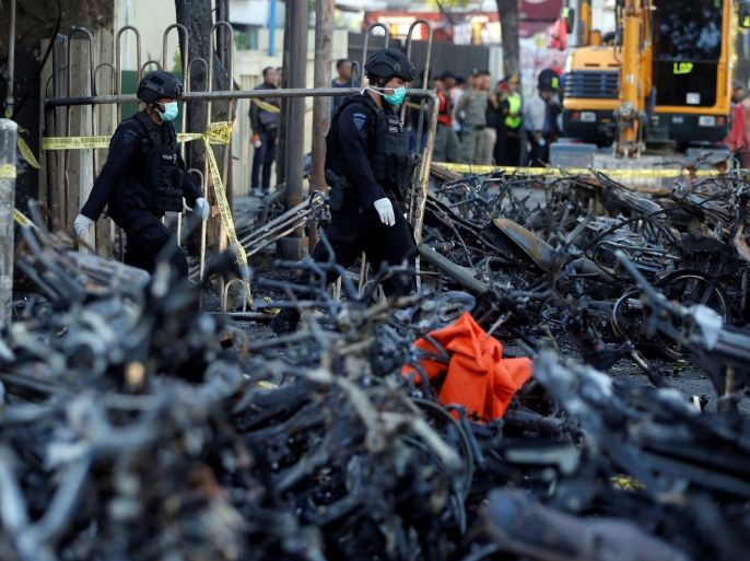 Members of the Indonesian Special Forces Police counter-terrorism squad walk by burned motorcycles following a blast at the Pentecost Church Central Surabaya (GPPS), in Surabaya, Indonesia May 13, 2018. REUTERS/Beawiharta