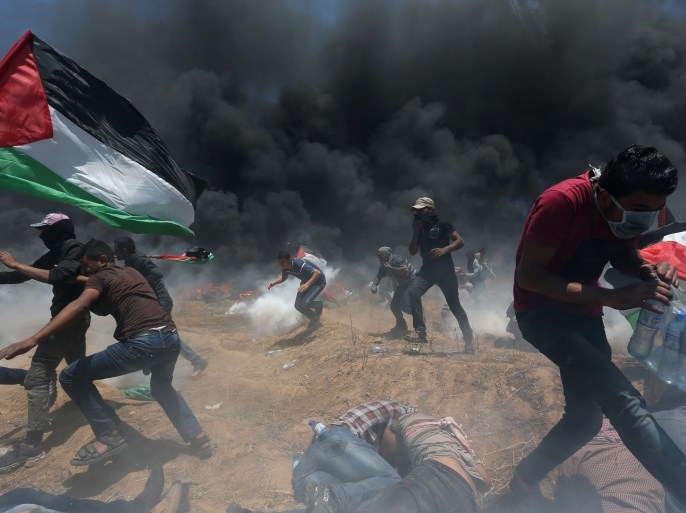 Palestinian demonstrators run for cover from Israeli fire and tear gas during a protest against U.S. embassy move to Jerusalem and ahead of the 70th anniversary of Nakba, at the Israel-Gaza border in the southern Gaza Strip May 14, 2018. REUTERS/Ibraheem Abu Mustafa