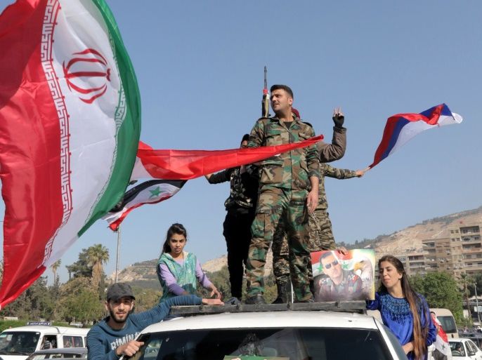 Syrian soldiers wave national flags along with Iranian and Russian flags as people gather to show support for the Syrian government in Umayyad square in Damascus