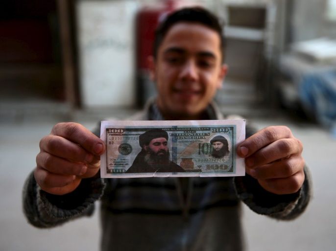 A boy poses while showing one of the fake U.S. 100 dollar banknotes depicting Islamic State's leader Abu Bakr al-Baghdadi (L) and al-Nusra Front's leader Abu Mohammed al-Joulani (R), that were dropped by Syrian army jets in the Douma neighborhood of Damascus, Syria December 27, 2015. REUTERS/Bassam Khabieh