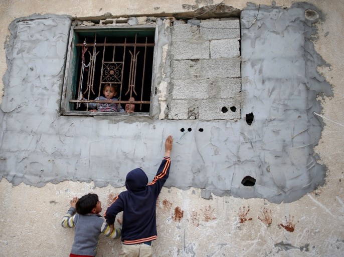 Palestinian children play as a girl held by her mother looks out of the window of house in the northern Gaza Strip February 12, 2018. Picture taken February 12, 2018. REUTERS/Mohammed Salem