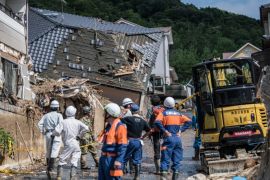HIROSHIMA, JAPAN - JULY 09: Emergency services members wait by buildings destroyed by a landslide on July 8, 2018 in Kumano near Hiroshima, Japan. Over 100 people are now believed to have died during floods and landslides triggered by 'historic' levels of heavy rain across central and western parts of Japan while more than 50,000 rescuers are racing to find survivors as temperatures rise. Japan's Prime Minister Shinzo Abe warned on Sunday of a 'race against time' to rescue flood victims as almost 2 million people are subject to evacuation orders and tens of thousands remain without electricity and water. (Photo by Carl Court/Getty Images)