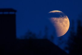 Full moon during an eclipse rises behind a house on the outskirts of Minsk