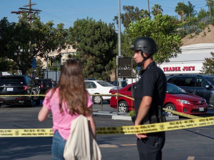 A police officer talks with a woman in a parking lot across the street from a Trader Joe's store where a hostage situation unfolded in Los Angeles, California, Saturday July 21, 2018. REUTERS/Andrew Cullen