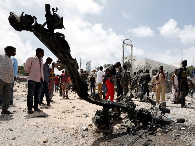 Somali security officers and civilians look at the wreckage of a vehicle destroyed at the scene where a speeding car exploded after it was shot at by police, outside the hotels near the presidential palace, in Mogadishu, Somalia July 14, 2018. REUTERS/Feisal Omar TPX IMAGES OF THE DAY