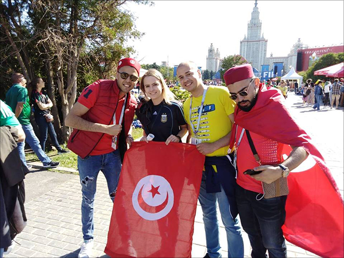 المشجع التونسي وليد الهذلي (يسار) يحمل علم تونس بصحبة عدد من الجماهير في موسكو (الجزيرة نت)