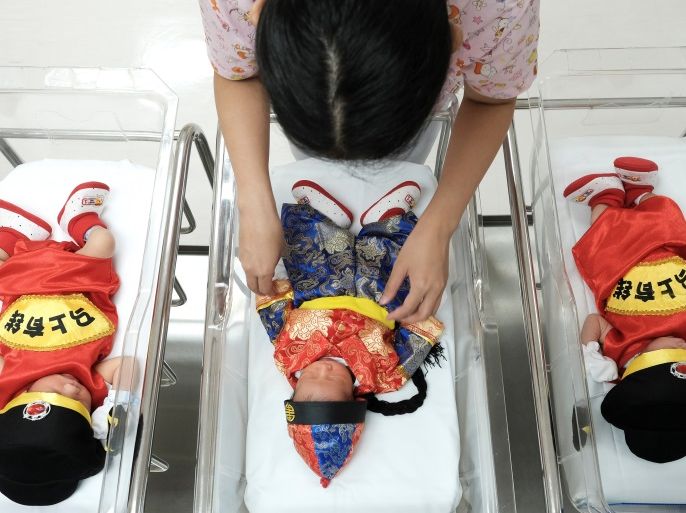 A nurse takes care of newborn babies wearing Chinese traditional costumes to celebrate the Chinese New Year at the nursery room of Paolo Chockchai 4 Hospital, in Bangkok, Thailand January 27, 2017. REUTERS/Athit Perawongmetha TPX IMAGES OF THE DAY