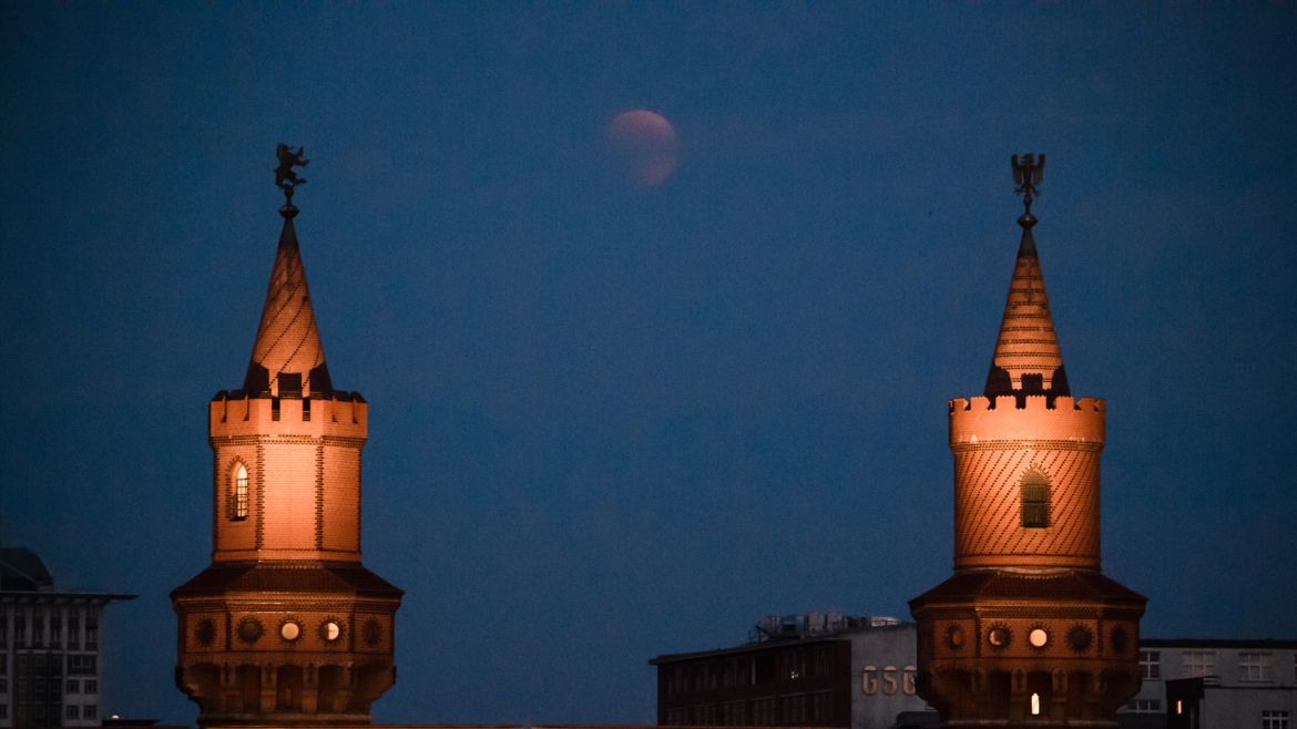 epa06914650 The red colored moon can be seen between the towers of the Oberbaumbruecke bridge in Berlin, 27 July 2018. The lunar eclipse on the night of 27 July 2018 will be the longest total lunar eclipse of the 21st century with the event spanning for over four hours, and the total eclipse phase lasting for 103 minutes. EPA-EFE/JAGADEESH NV CBF