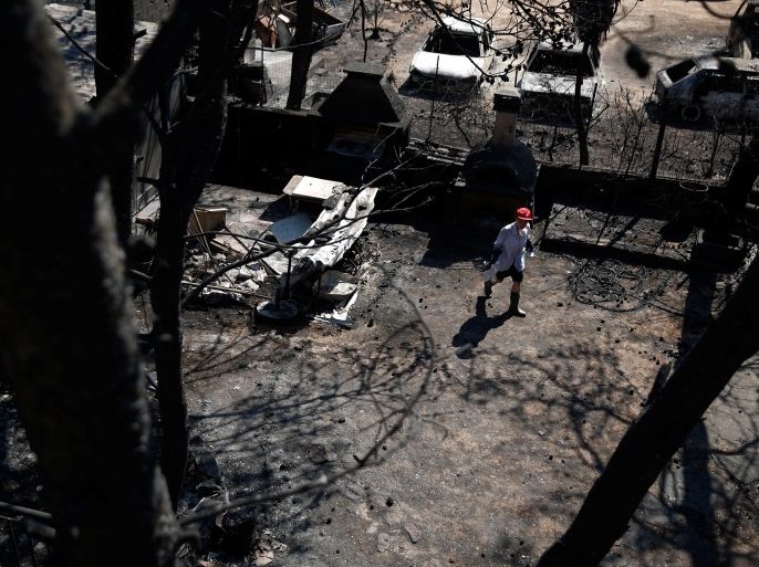 A woman makes her way in the yard of her house following a wildfire in the village of Mati, near Athens, Greece, July 27, 2018. REUTERS/Costas Baltas