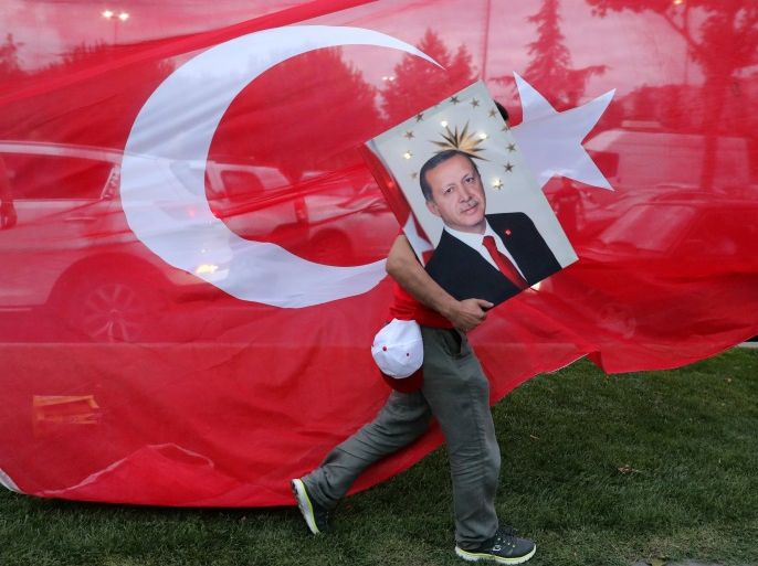 A supporters of Turkish President Tayyip Erdogan holds his picture in front of a Turkish flag, in front of Turkey's ruling AK Party (AKP) headquarters in Istanbul,Turkey, June 24, 2018. REUTERS/Goran Tomasevic TPX IMAGES OF THE DAY