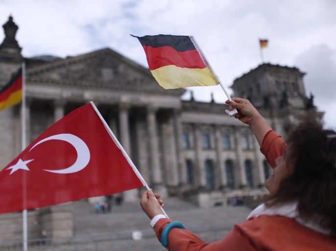 A demonstrator holds Turkish and German flags in front of the Reichstag, the seat of the lower house of parliament Bundestag in Berlin, Germany, June 1, 2016, as she protests against a disputed vote in Germany's parliament on Thursday, on a resolution that labels the killings of up to 1.5 million Armenians by Ottoman forces as genocide. REUTERS/Hannibal Hanschke