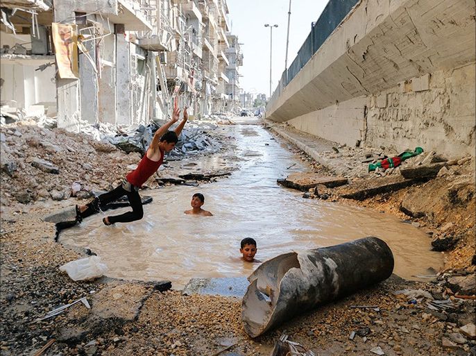 A boy dives into a crater filled with water in the Al-Shaar neighborhood. The crater was made by a barrel bomb. (Hosam Katan)