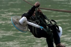 A villager carries an electric fan while zipping across the Nu River in Nujiang Lisu Autonomous Prefecture in Yunnan province, China, March 28, 2018. Picture taken March 28, 2018. REUTERS/Aly Song