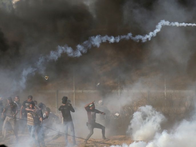 Palestinians hurl stones as tear gas fired by Israeli troops during a protest at the Israel-Gaza border in the southern Gaza Strip July 6, 2018. REUTERS/Ibraheem Abu Mustafa