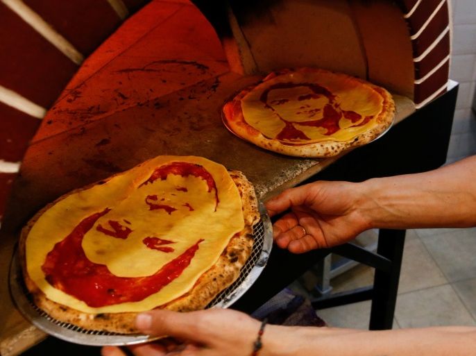Cook Valery Maksimchik takes pizzas decorated with portraits of Portugal's Cristiano Ronaldo and Uruguay's Luis Suarez out of an oven at the Hop Head cafe in St. Petersburg, Russia June 29, 2018. REUTERS/Anton Vaganov