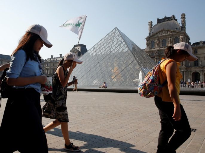 Chinese tourists walk past the Louvre Pyramid designed by Chinese-born U.S. Architect Ieoh Ming Pei outside the Louvre Museum in Paris, France, July 26, 2018. Picture taken July 26, 2018. REUTERS/Philippe Wojazer