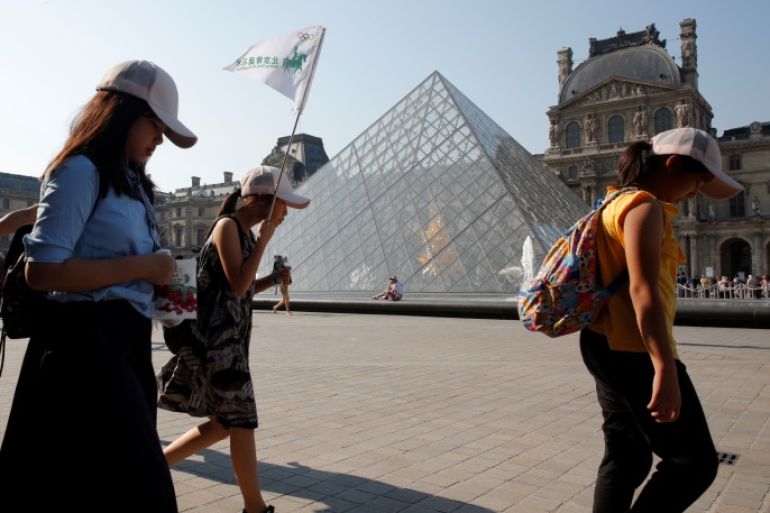 Chinese tourists walk past the Louvre Pyramid designed by Chinese-born U.S. Architect Ieoh Ming Pei outside the Louvre Museum in Paris, France, July 26, 2018. Picture taken July 26, 2018. REUTERS/Philippe Wojazer