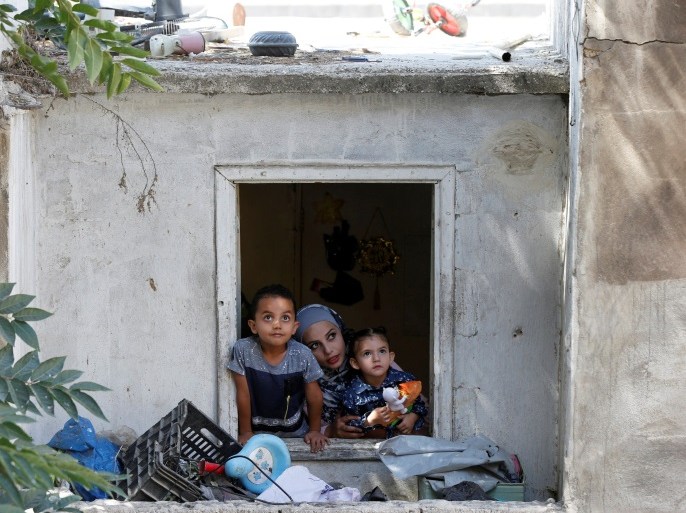 27-year-old Syrian refugee Alaa Masalmeh and her children, 5-year-old Samer and 3-year-old Mieral, look out of their home's window in Amman, Jordan, August 1, 2018. Picture taken August 1, 2018. REUTERS/Muhammad Hamed