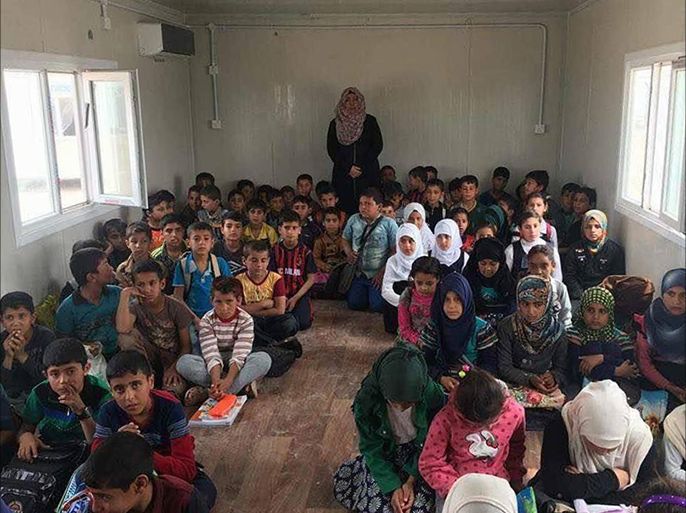 أطفال عراقيون يجلسون على الأرض في إحدى الصفوف المدرسية