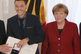 German President Joachim Gauck and Chancellor Angela Merkel pose with national soccer player Mesut Ozil (C) after the team was awarded the
