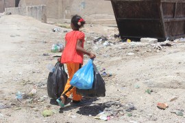 فتاة تقوم بالقاء النفايات في احد الحاويات بعد تكدسها امام المنازل