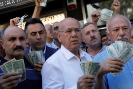 Businessmen holding U.S. dollars stand in front of a currency exchange office in response to the call of Turkish President Tayyip Erdogan on Turks to sell their dollar and euro savings to support the lira, in Ankara, Turkey August 14, 2018. REUTERS/Umit Bektas