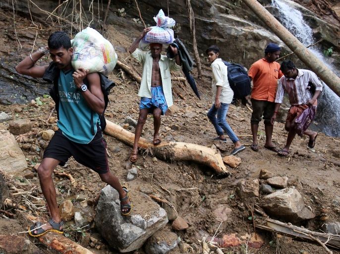 Flood victims carry relief material as they walk through a damaged area after floods, at Nelliyampathy Village in the southern state of Kerala, India, August 21, 2018. REUTERS/Amit Dave