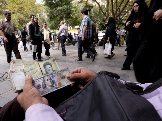 A money changer displays U.S. and Iranian banknotes at the Grand Bazaar in central Tehran October 7, 2015. To match Insight IRAN-BANKING/ REUTERS/Raheb Homavandi/TIMA/File Photo ATTENTION EDITORS - THIS IMAGE WAS PROVIDED BY A THIRD PARTY. EDITORIAL USE ONLY.