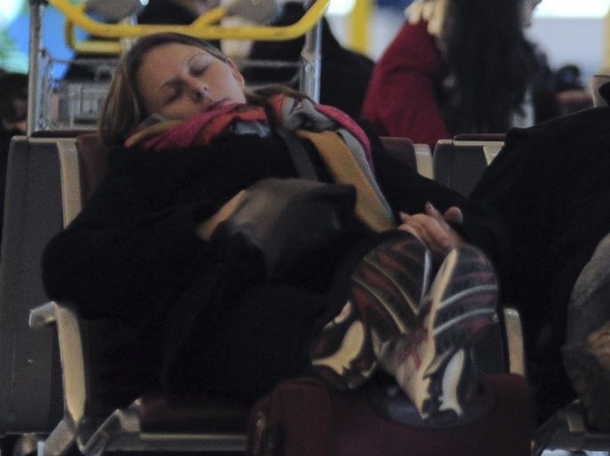 Passengers sleep in a terminal at the Charles-de-Gaulle aiport in Roissy, near Paris, after flights were cancelled due to snow and freezing temperatures December 24, 2010. The French government expects hundreds of people to spend Christmas Eve night at Roissy, as snowfall in the north and east of the country and a lack of de-icing fluid continued to disrupt transport services. REUTERS/Julien Muguet (FRANCE - Tags: ENVIRONMENT TRANSPORT)
