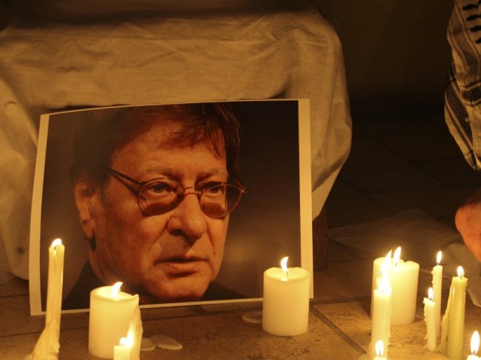 A candle is placed in front of a picture of late Palestinian poet Mahmoud Darwish, during a candle-lit vigil in Amman August 11, 2008. Darwish, whose poetry encapsulated the Palestinian cause, will be buried in the West Bank on Wednesday, a day later than planned, Palestinian officials said. REUTERS/Ali Jarekji (JORDAN)