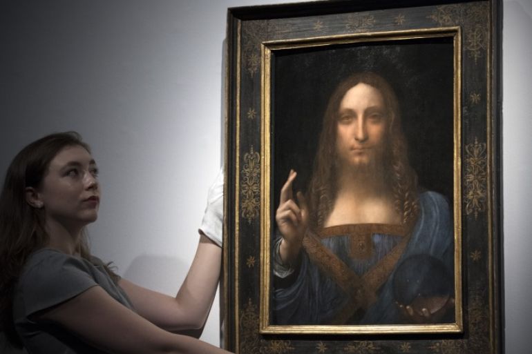 LONDON, ENGLAND - OCTOBER 24: A member of staff poses with a painting by Leonardo da Vinci entitled 'Salvator Mundi' before it is auctioned in New York on November 15, at Christies on October 24, 2017 in London, England. The painting is the last Da Vinci in private hands and is expected to fetch around 100,000,000 USD. (Photo by Carl Court/Getty Images)